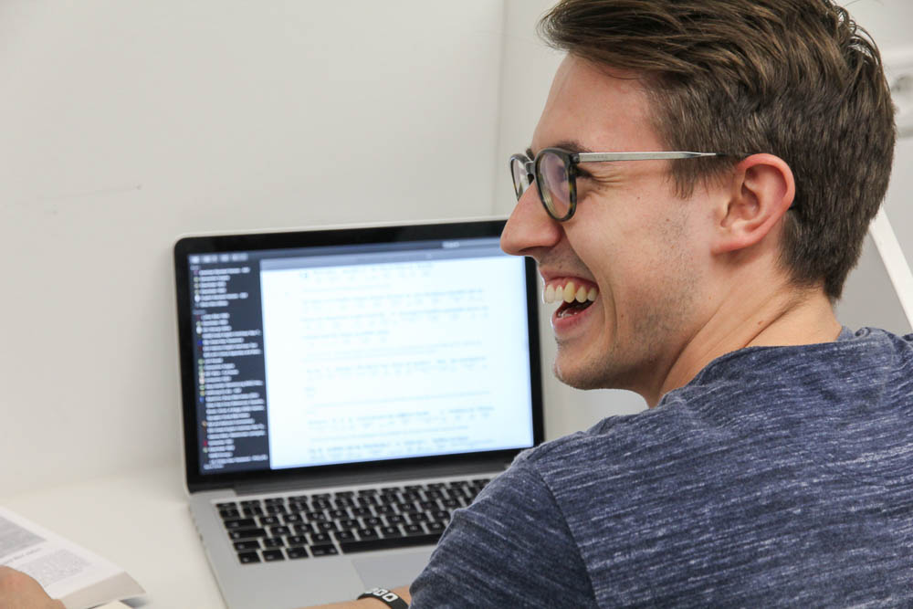 Student lacht beim Lernen am Computer